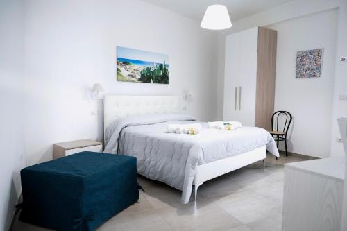 a white bedroom with a bed and a blue ottoman at Bed & Breakfast Terra d'Arneo in Leverano