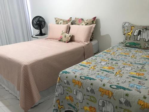 um quarto com 2 camas e uma colcha com animais em Quartos em APART FAMILIAR no circuito do carnaval de Salvador em Salvador