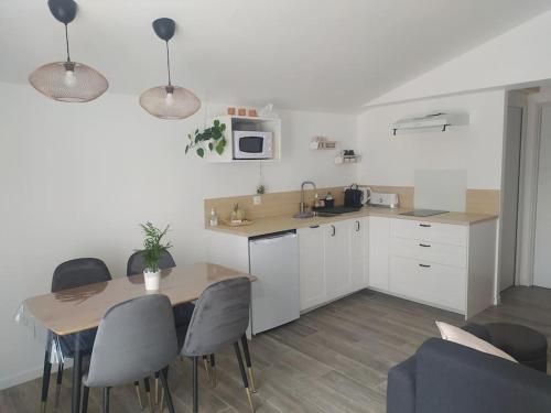 uma cozinha com mesa e cadeiras e uma cozinha com armários brancos em Pied à terre familial au pied du Luberon em Mérindol