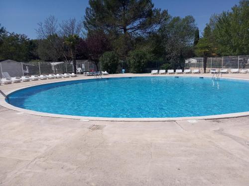 une grande piscine bleue avec des chaises et des tables dans l'établissement Mobil home 6 places, à La Roque-dʼAnthéron