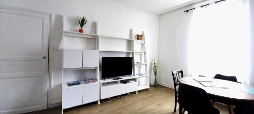 een witte woonkamer met een tafel en een televisie bij MIRA BELLA - Centre ville avec jardin in Saumur