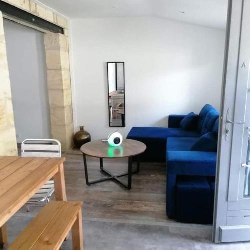 a living room with a blue couch and a table at Maison de bourg à 5 minutes de Soulac Sur Mer in Talais