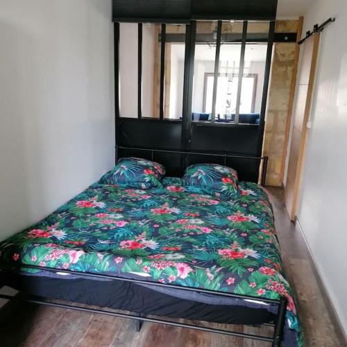 Bett mit Blumendecke in einem Zimmer in der Unterkunft Maison de bourg à 5 minutes de Soulac Sur Mer in Talais