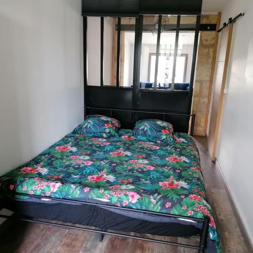 - un lit avec une couette à fleurs dans l'établissement Maison de bourg à 5 minutes de Soulac Sur Mer, à Talais