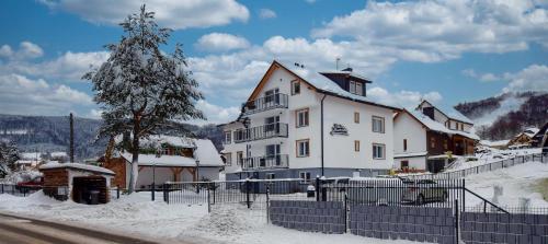 a large white house with snow on the ground at Apartamenty Dolina Jawornika in Wisła
