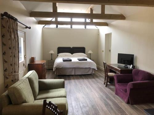 a bedroom with a bed and a couch and a table at The Stables in Colchester