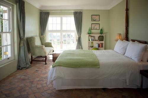 a bedroom with a bed and a chair and a window at Hawksmoor House in Stellenbosch