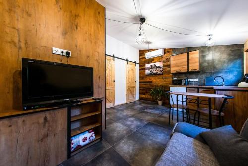 a living room with a large television and a kitchen at Domek Trolla in Sieraków