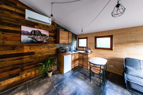 a kitchen with wooden walls and a table and chairs at Domek Trolla in Sieraków