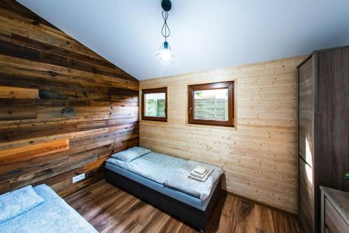a room with a bed in a wooden wall at Domek Trolla in Sieraków