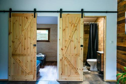 La salle de bains est pourvue de 2 portes en bois et de toilettes. dans l'établissement Domek Trolla, à Sieraków