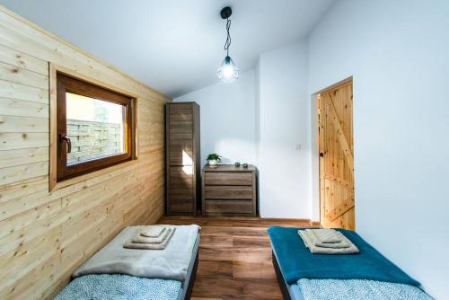 two beds in a room with wooden walls and a window at Domek Trolla in Sieraków
