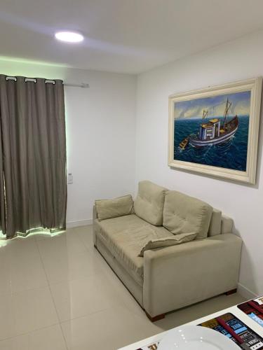 a living room with a couch and a painting of a boat at Golden Lake - Vista Lagoa in Arraial do Cabo