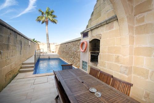 a swimming pool with a wooden bench next to a building at Ta' Rozi 5 Bedroom Farmhouse with Private Pool in Għarb