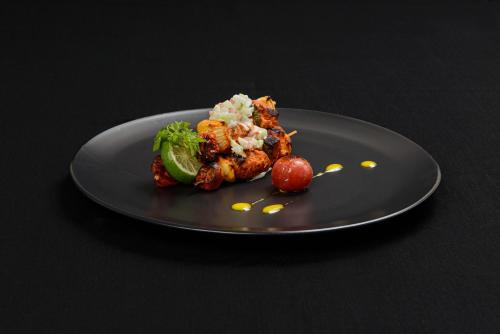 a black plate with food on a black table at Gazelle International Hotel in Kokopo