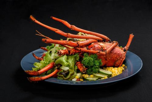 a plate of food with a lobster on top of broccoli at Gazelle International Hotel in Kokopo