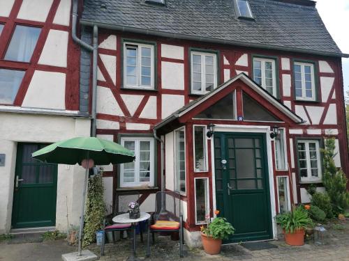 un edificio rojo y blanco con una mesa y una sombrilla en Hof Idarwald, en Horbruch
