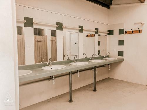 ein öffentliches Bad mit 4 Waschbecken und Spiegeln in der Unterkunft Lodg'ing Nature Camp Dordogne in Lacave