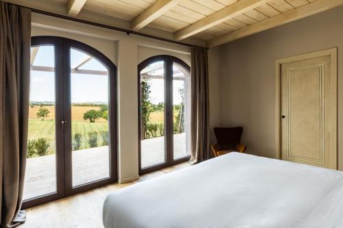 a bedroom with a bed and two windows at Country House Oliveto sul Lago in San Nicolò