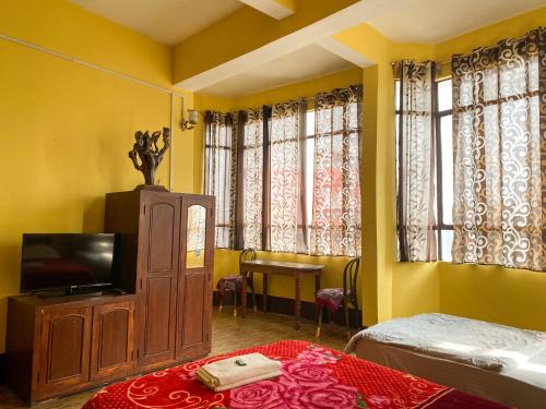 a room with a television and a bed and a table at King Thai Hotel and Restaurant in Kalimpong