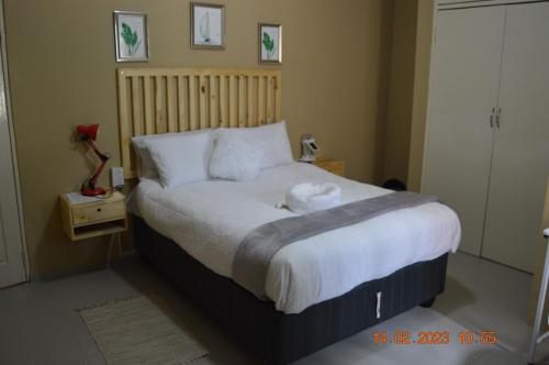 1 dormitorio con 1 cama grande con sábanas blancas en Glorious Home Bed & Breakfast en Mochudi