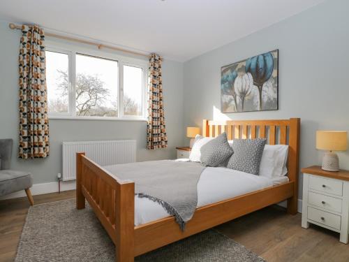 a bedroom with a wooden bed and two windows at Birch House in Corsham