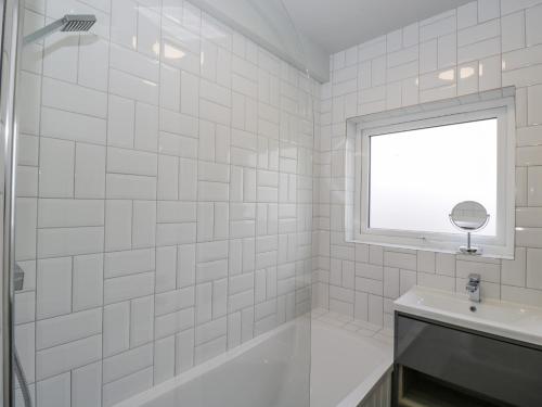 a white tiled bathroom with a shower and a sink at Birch House in Corsham
