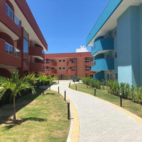 a walkway in front of a building with palm trees at Golden Lake - 1 quarto in Arraial do Cabo