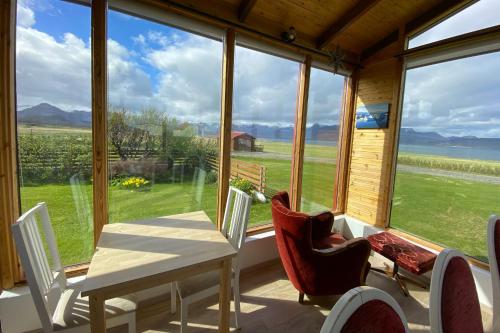 a dining room with a table and chairs in front of a window at Sudur-Bár Guesthouse in Grundarfjordur