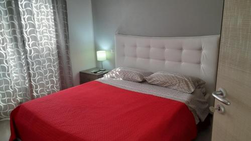a bedroom with a large bed with a red blanket at I Faraglioni Comfort Rooms in Terrasini