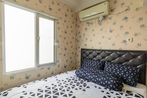 um quarto com uma cama e duas janelas em Cozy 2 Bedroom Apartemen Pavilion Permata em Dukuhpakis