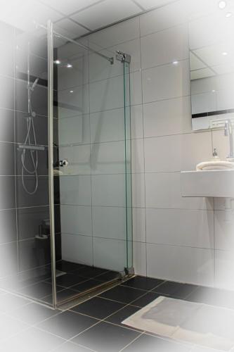 a glass shower in a bathroom with a sink at Hotel de Boegschroef in Delfzijl