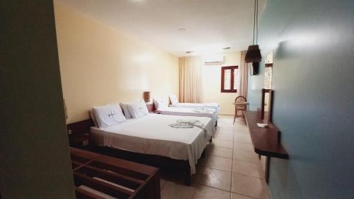 a room with two beds in a hotel room at Albacora Praia Hotel in Japaratinga