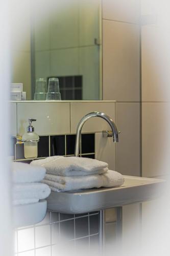 a bathroom sink with towels and a faucet and a mirror at Hotel de Boegschroef in Delfzijl