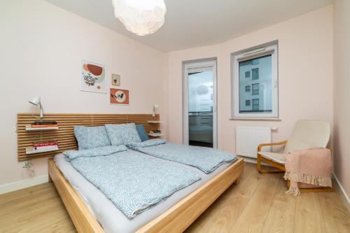 a bedroom with a large bed and a chair at Apartament Modern w Albatross Towers Gdańsk in Gdańsk