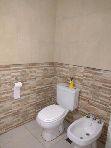 a bathroom with a white toilet and a sink at Casa de campo Los Cardenales in Rafaela