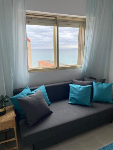 Sofá con almohadas en una habitación con ventana en Oasis Paradise Apartment La Manga en La Manga del Mar Menor