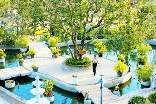 a woman walking through a garden with trees and water at KNN Luxury Hill in Sen Monorom