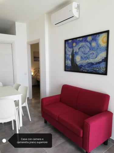 a living room with a red couch and a painting on the wall at Fascino del Cilento in Caprioli