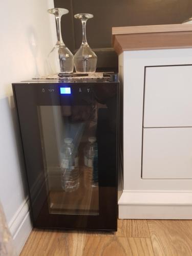 a microwave oven with two glasses on top of it at Sea-Quinn Views in Wallasey