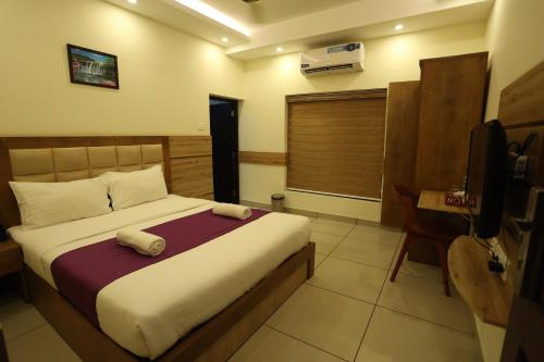 a bedroom with a bed and a television in it at Balaji Regency Kanhangad in Kānnangād