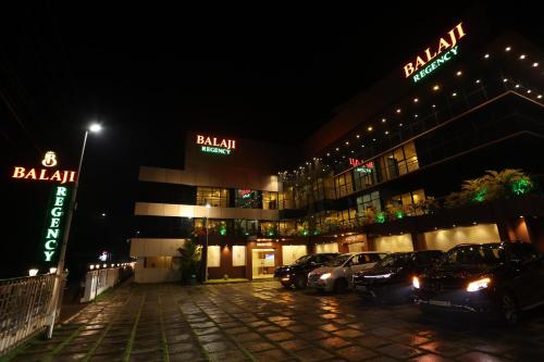 a building with cars parked in a parking lot at night at Balaji Regency Kanhangad in Kānnangād