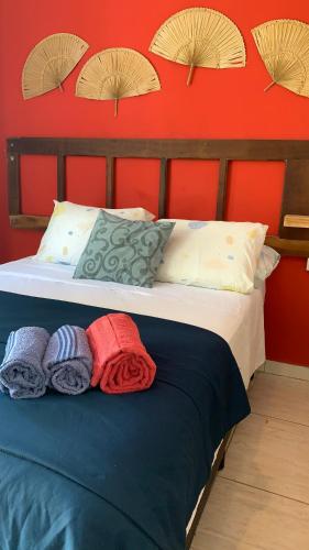 a bed with pillows on it with a red wall at Pousada Suítes Sete Mares in Guarujá