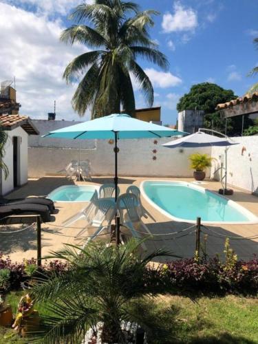 a swimming pool with two chairs and an umbrella at Pousada Grauça in Cacha Pregos