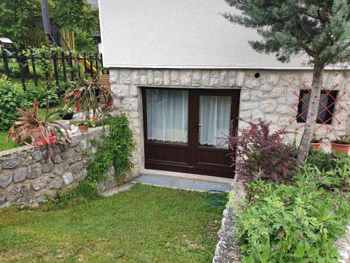 a small stone house with a brown door at Sobe Ćuskić in Bohinj