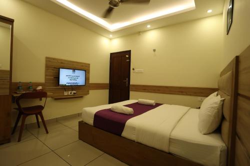 a hotel room with a bed and a television at Balaji Regency Kanhangad in Kānnangād