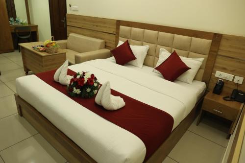 a bedroom with a large bed with red and white pillows at Balaji Regency Kanhangad in Kānnangād
