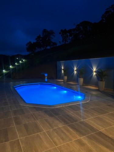 una piscina por la noche con luces en Recanto da Roca, en Domingos Martins