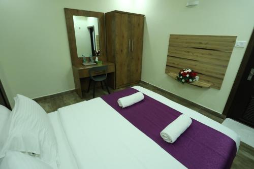 a bedroom with a bed with purple sheets and a desk at Balaji Regency Kanhangad in Kānnangād