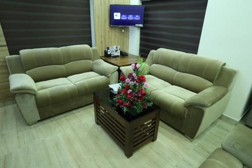a living room with two couches and a table with flowers at Balaji Regency Kanhangad in Kānnangād